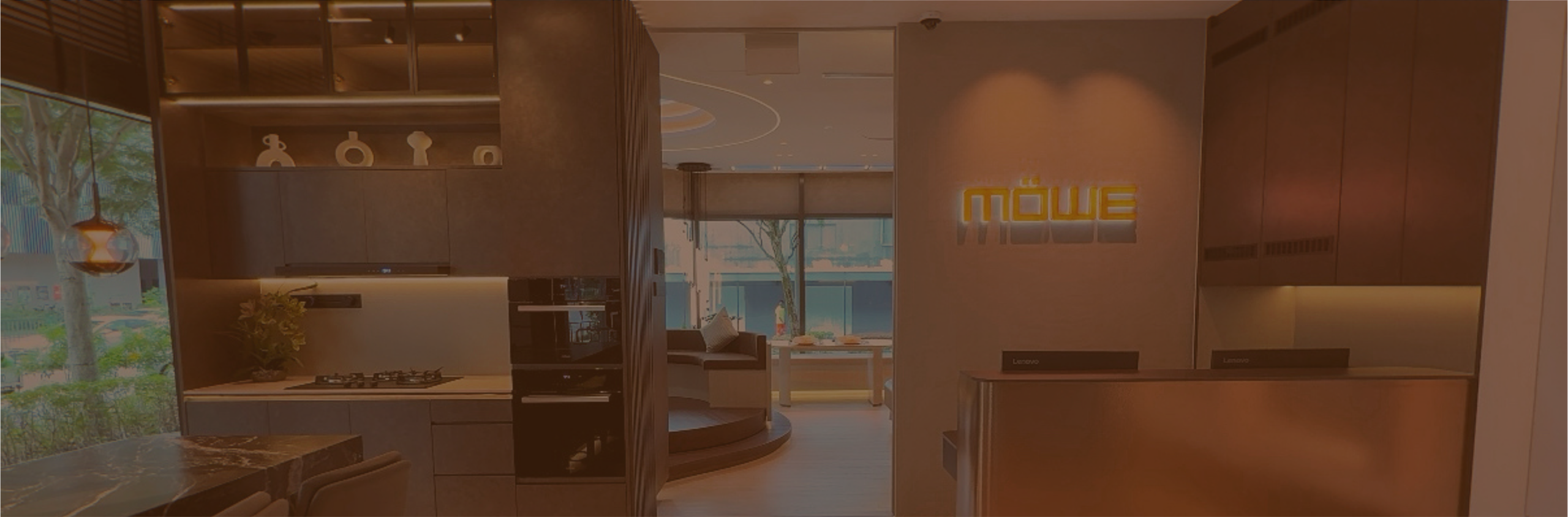 Modern kitchen showroom with built-in appliances and a glowing Möwe sign on the wall